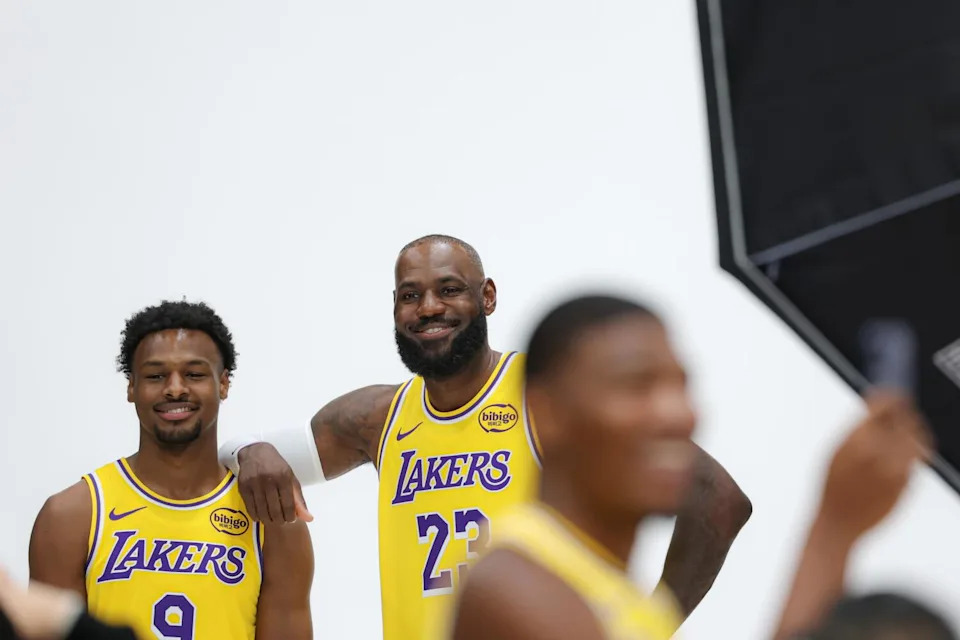 Bronny and LeBron James pose for photos at Lakers media day as Rui Hachimura takes a selfie in front of them.