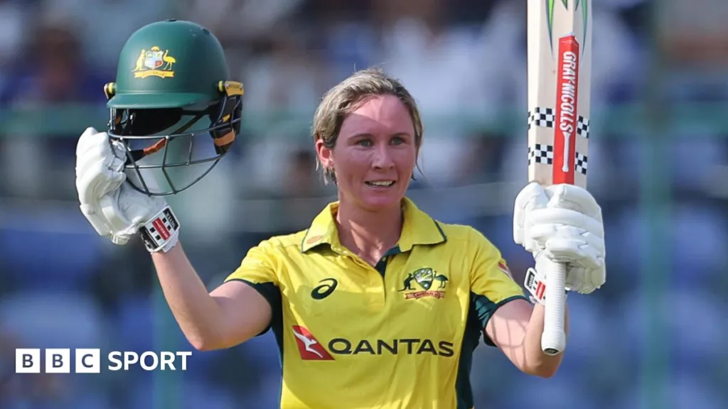 Australia batter Beth Mooney raises her helmet and bat to celebrate hitting a century against India in the third ODI